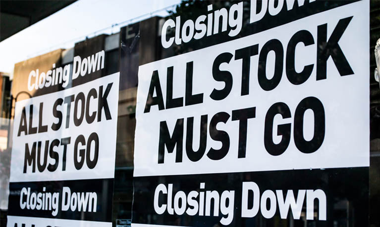 Front of store with signage for 'all stock must go' closing down