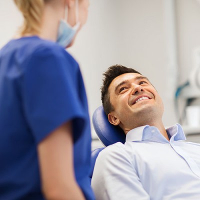 female-dentist-standing-up-male-student-sitting-and-smiling