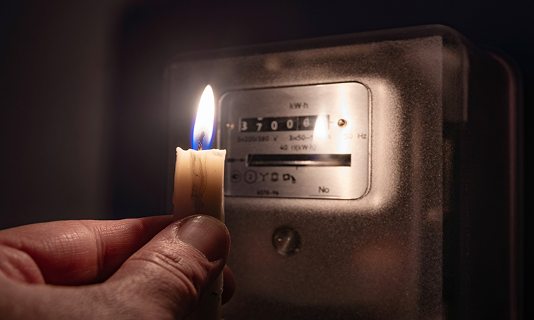 A candle being held in front of an electricity meter