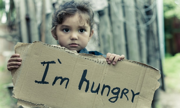 A child holding up some cardboard that says "I'm hungry"