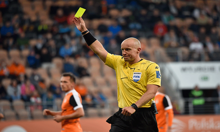 Football referee holding up a yellow card on the football pitch