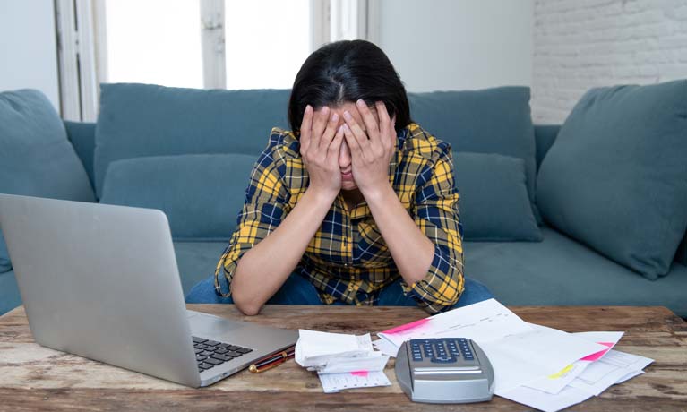 Female with head in hands working on laptop at desk