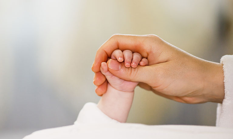 Close up mother holding tiny hand of little newborn